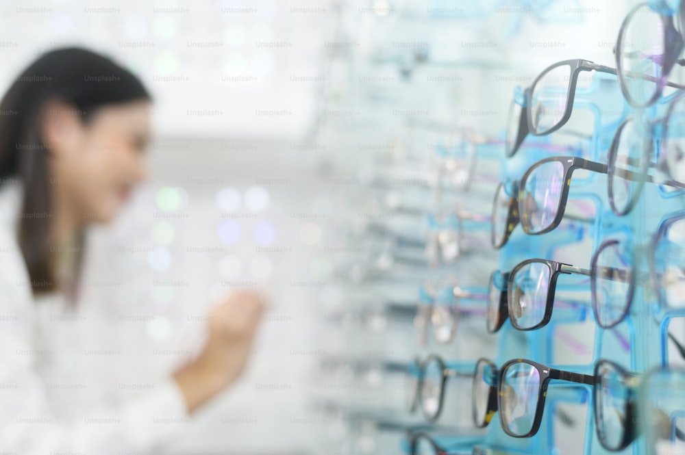 A young female customer choosing glasses in optical center, Eyecare concept.