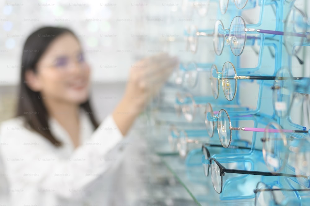 A young female customer choosing glasses in optical center, Eyecare concept.