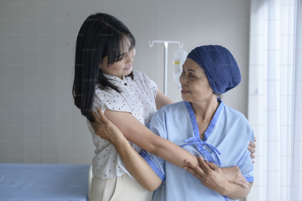 Cancer patient woman wearing head scarf and her supportive daughter in hospital, health and insurance concept.