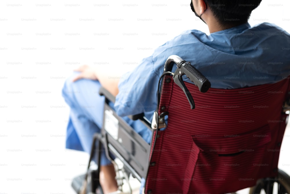 Male patient sitting wheelchair looking through window in hospital.