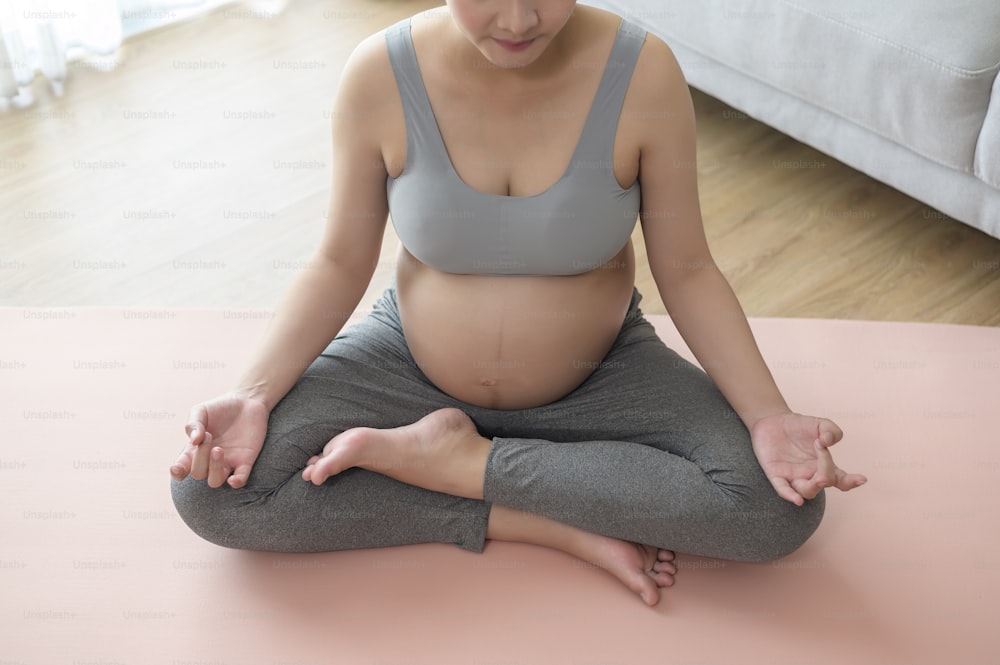 Young pregnant woman doing yoga at home, healthcare and pregnancy care concept
