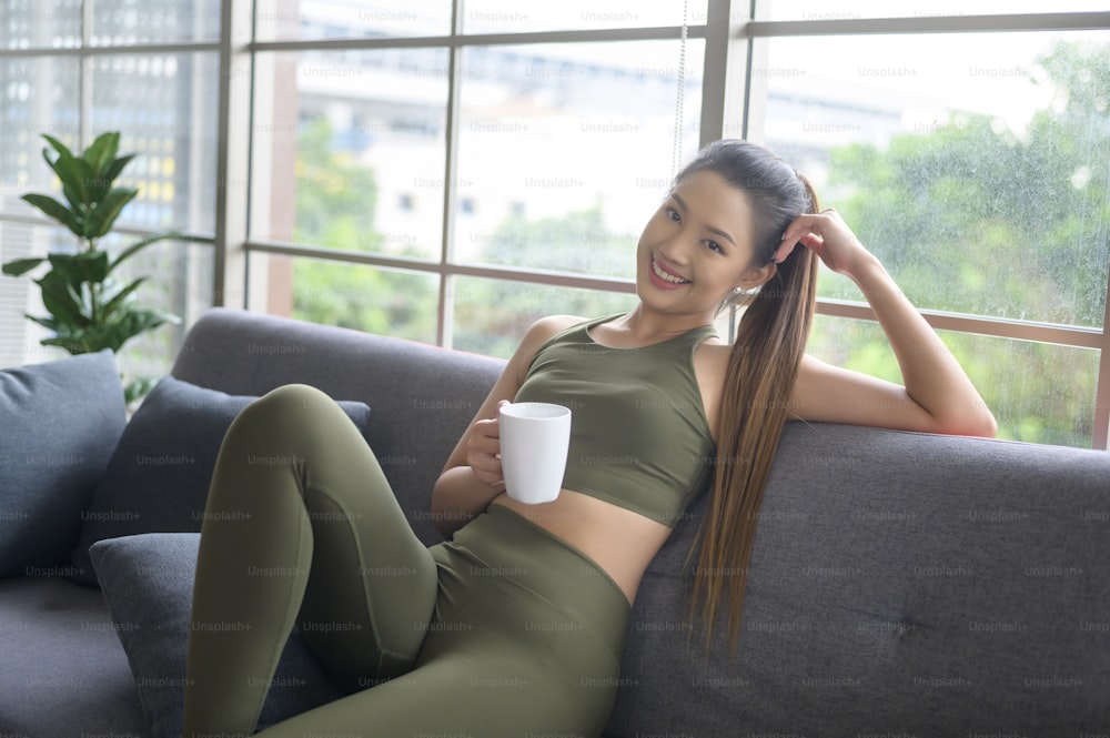 Young fitness woman in sportswear having a cup of coffee after exercising at home, Healthy and Lifestyles.