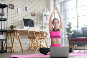 Fit young woman practicing yoga at home via online class with professional instructor, sport and healthy lifestyle concept.