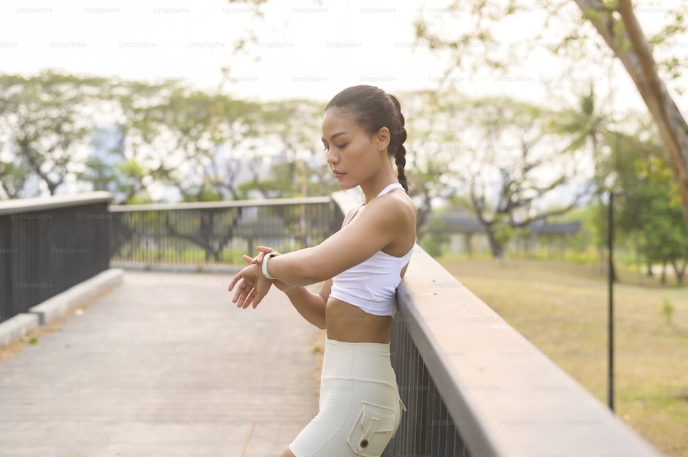 도시 공원, 건강 및 라이프 스타일에서 운동하는 동안 스마트 시계를 사용하는 운동복을 입은 젊은 피트니스 여성.