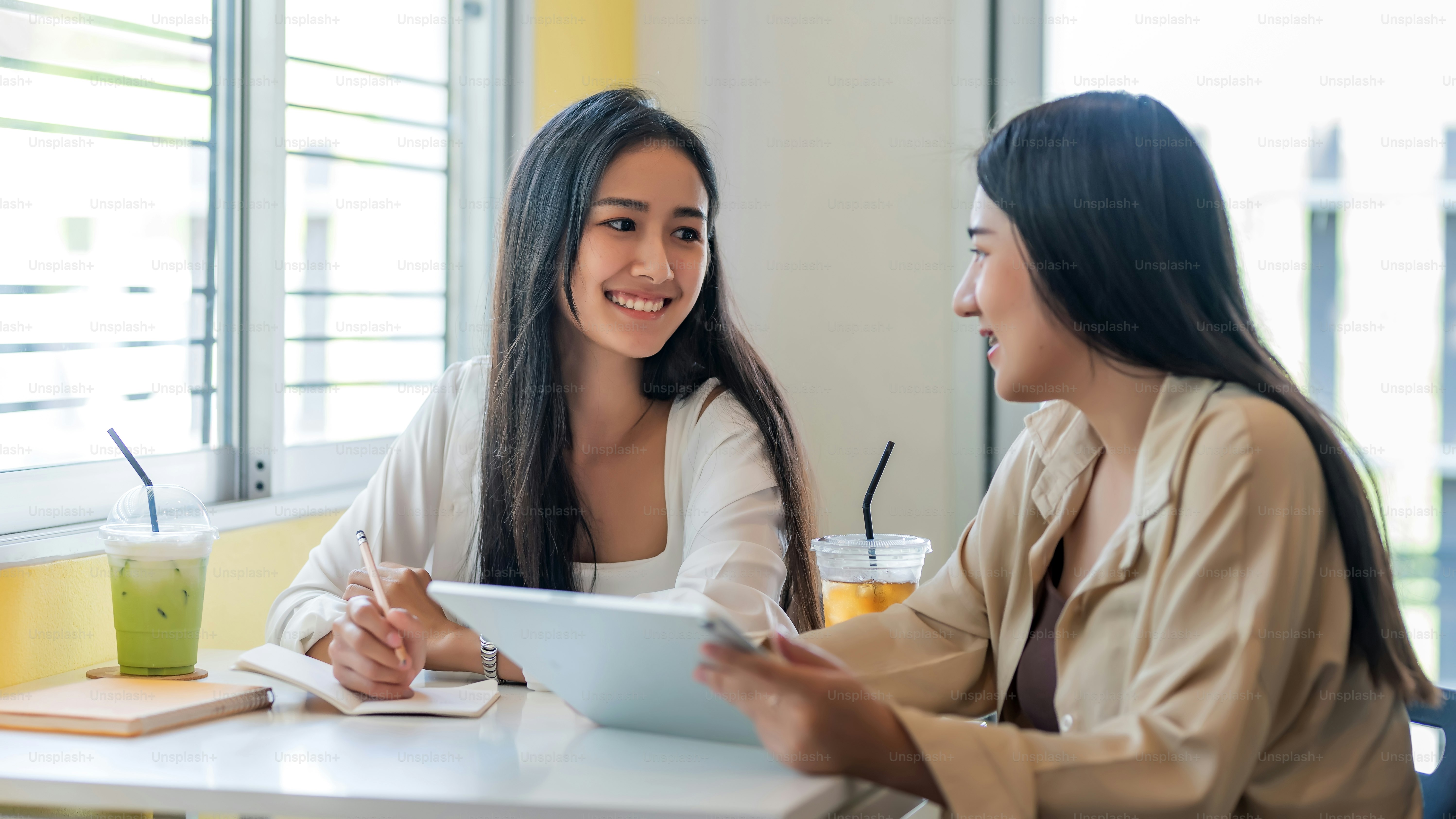 Two young Asian businesswoman is happy working on presentations using papers and tablet placed at the office.