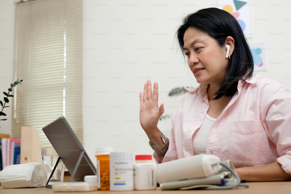 Visita en línea al médico de telemedicina de mujer asiática con computadora en casa