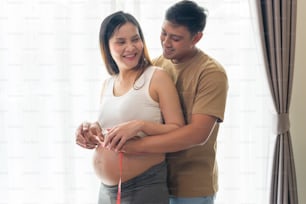 Mujer embarazada joven que mide centímetro de vientre, atención médica y cuidado del embarazo