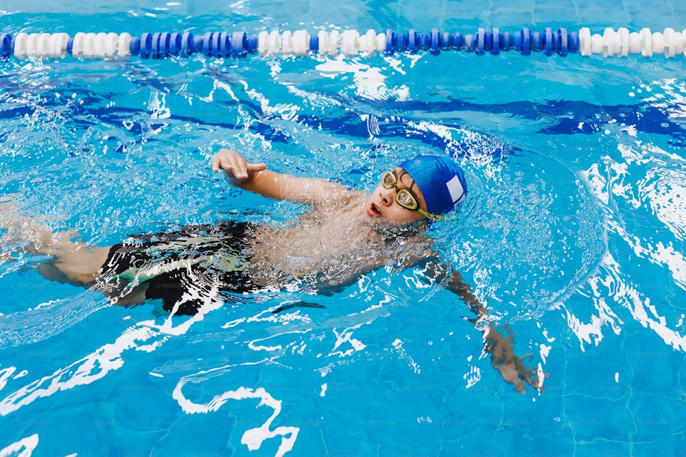 Niño con gorro de baño y gafas de natación en la piscina el niño participa  en la sección de natación