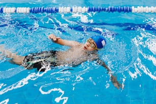 latin child boy swimmer wearing cap and goggles in a swimming training at the Pool in Mexico Latin America