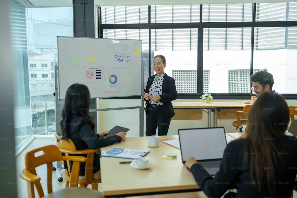 アジアのビジネスパーソンは、オフィスでの計画、投資、マーケティングを分析します。新しいプロジェクトと分析データドキュメントをブレインストーミングするためのビジネスミーティング。