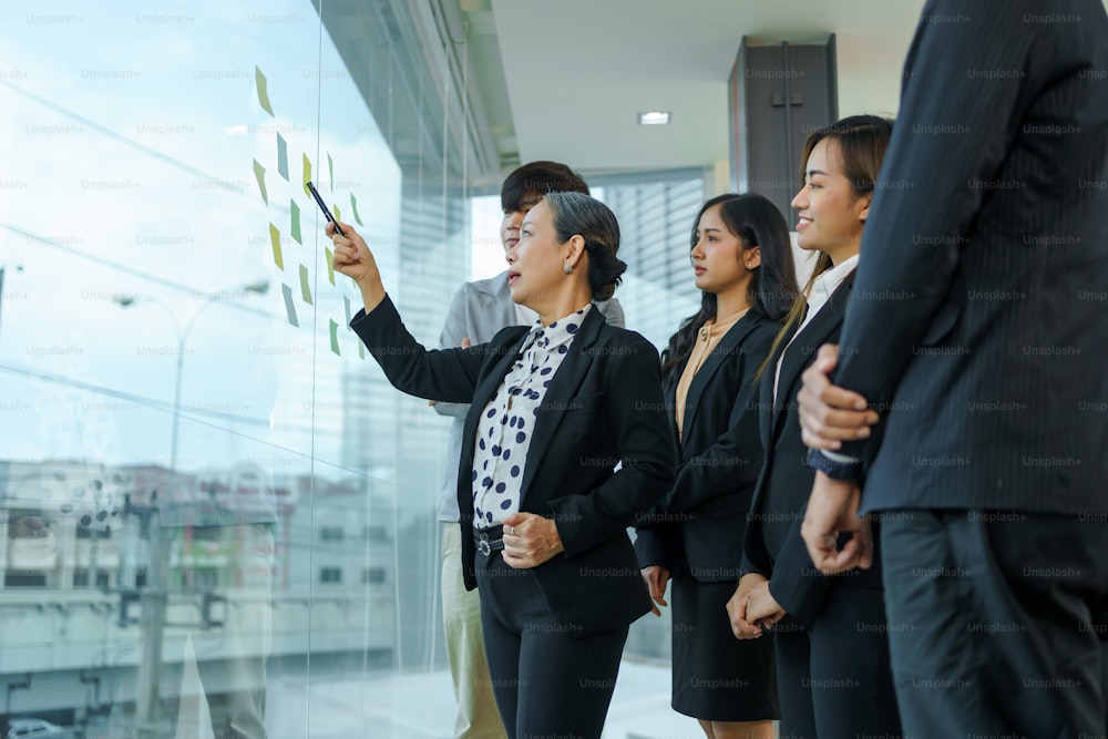Asiatische Geschäftsleute, die planen, analysieren Investitionen und Marketing im Büro. Geschäftstreffen zum Brainstorming des neuen Projekt- und Analysedatendokuments.