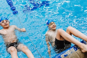 ラテンアメリカのプールで水泳のトレーニングで帽子とゴーグルを身に着けているラテンチャイルドの男の子の水泳選手