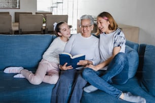 avó e neta hispânicas lendo um livro no sofá em casa no México América Latina
