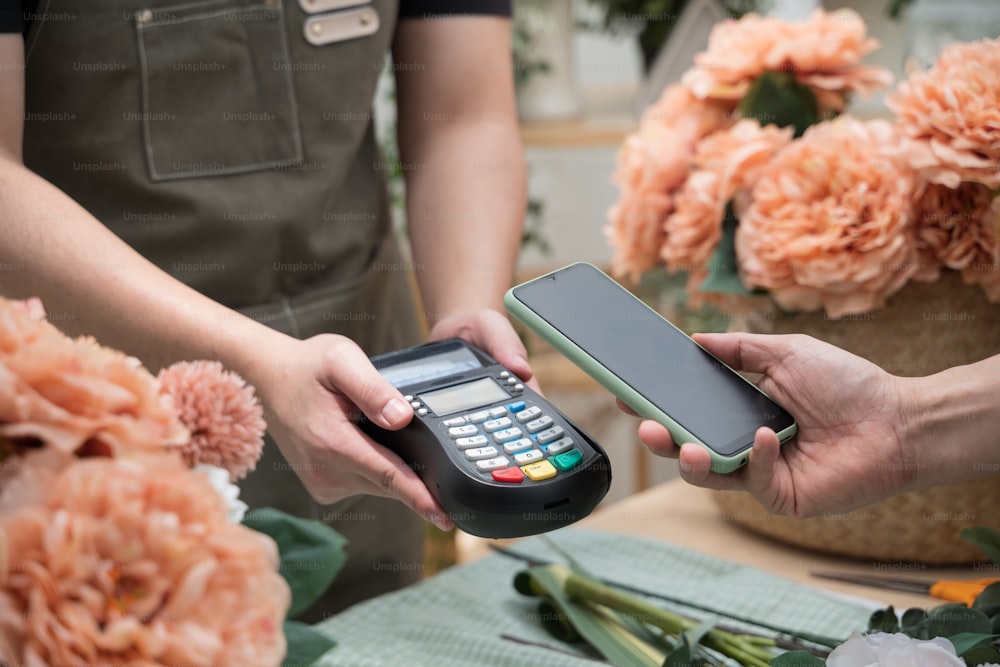 Cliente che utilizza il telefono per il pagamento nel negozio di fiori. Pagamento Nfc