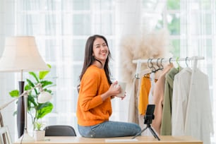 smart attractive smiling asian female business owner entrepreneur hand hold coffee cup portrait shot looking at camera with confident,woman sitting on table at home studio