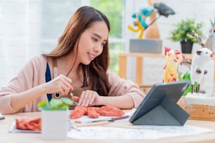 アジアの女性は、自宅で趣味の粘土彫刻オンラインコース、エプロンコスチュームでオンラインでタブレットストリーミングコースから勉強をするヤングアダルト、自宅でアジアのカジュアルなライフスタイルのために週末を過ごします
