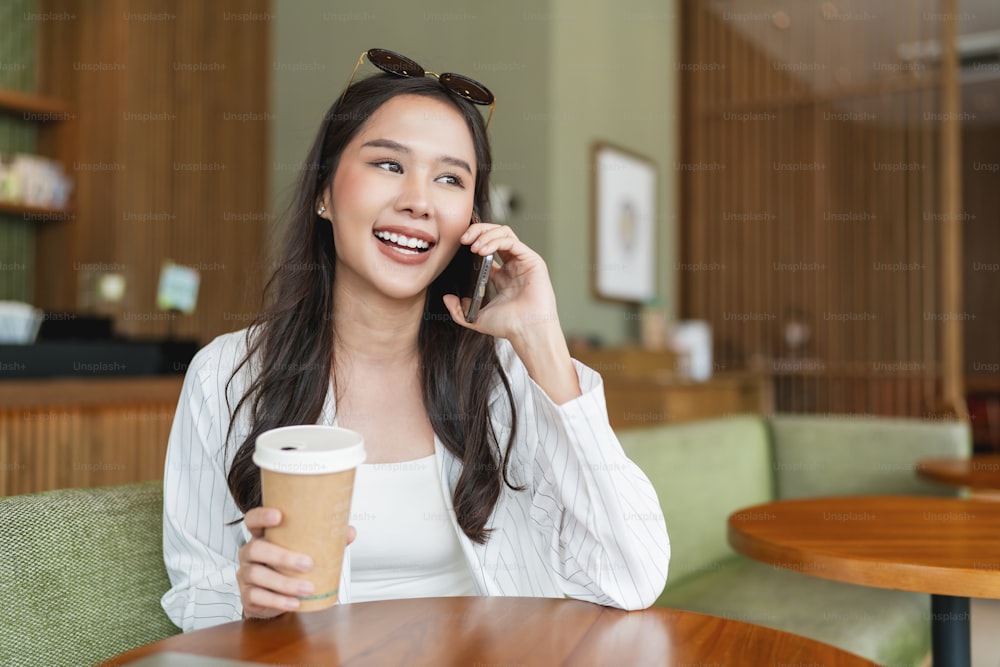 attractive smart casual asian female hand typing chat using smartphone telecommunication positive attitude smile in cafe casual,smart business owner entrepreneur working with smartphone in cafe
