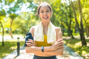 スポーツアジアの女性の十代の肖像画は、公共の公園で朝のジョギング健康的なルーチン活動の日曜を実行している間に撮影され、アジアの女性はスポーツウェアを着用し、ランニングエクササイズから休憩しながらカメラを見て笑顔を浮かべます