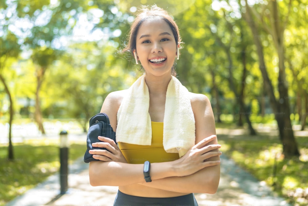 Portrait d’adolescent de femme asiatique de sport photographié pendant que le matin courir jogging activité de routine saine dimanche au parc public, femme asiatique porter des vêtements de sport sourire regarder la caméra tout en faisant une pause de l’exercice de course