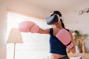 Virtual Metaverse Augmented Reality asiático adulto feminino trabalhando boxe em VR headset treinamento aeróbico para boxe punch em realidade virtual na sala de estar fundo interior da casa