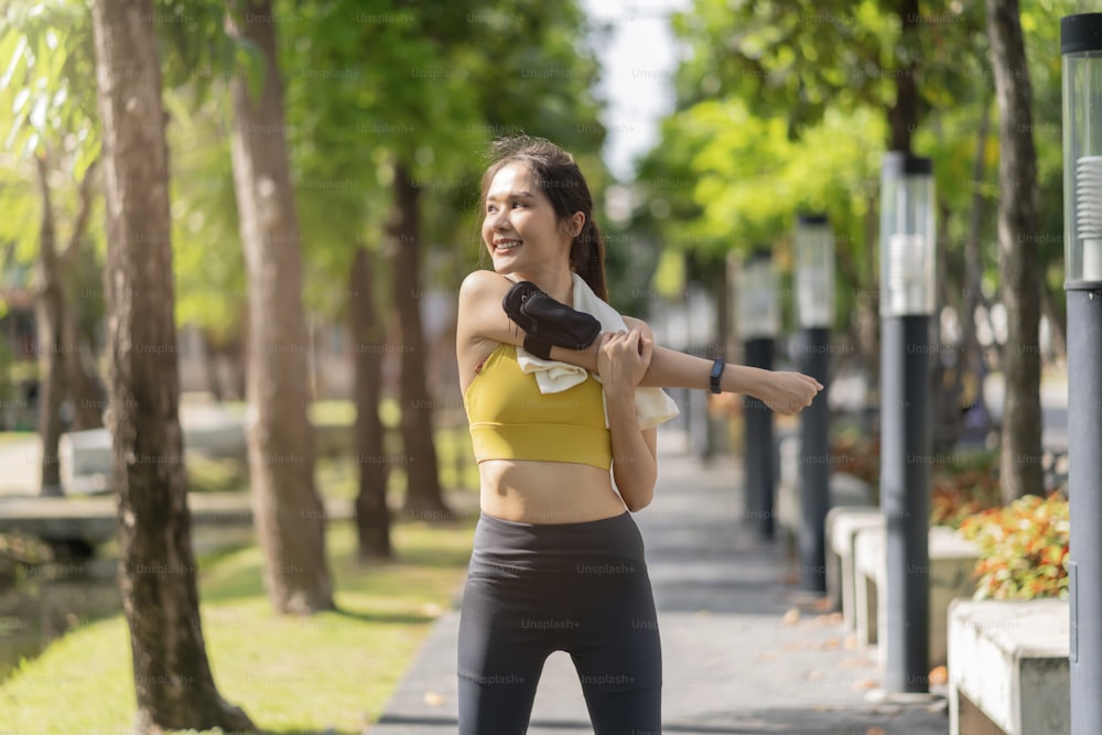 asian cheerful young female adult Attractive and strong morning stretching before running at the park Sports concept. Healthy lifestyle Young fitness woman runner stretching before morning jogging