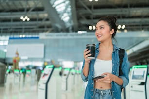 expat digital nomad travel and work,asian cheerful female casual cloth walking while using smartphone booking check in flight online ticket information application at airport terminal travel concept