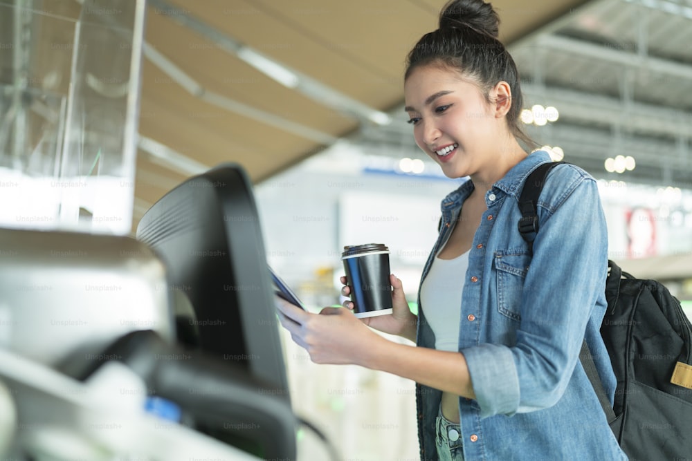 Enregistrement facile dans la main souriante d’une femme asiatique à l’aide d’un code à barres de balayage d’application pour smartphone pour vérifier les informations sur le siège d’avion via le terminal d’aéroport de comptoir d’application, transport d’application de technologie intelligente