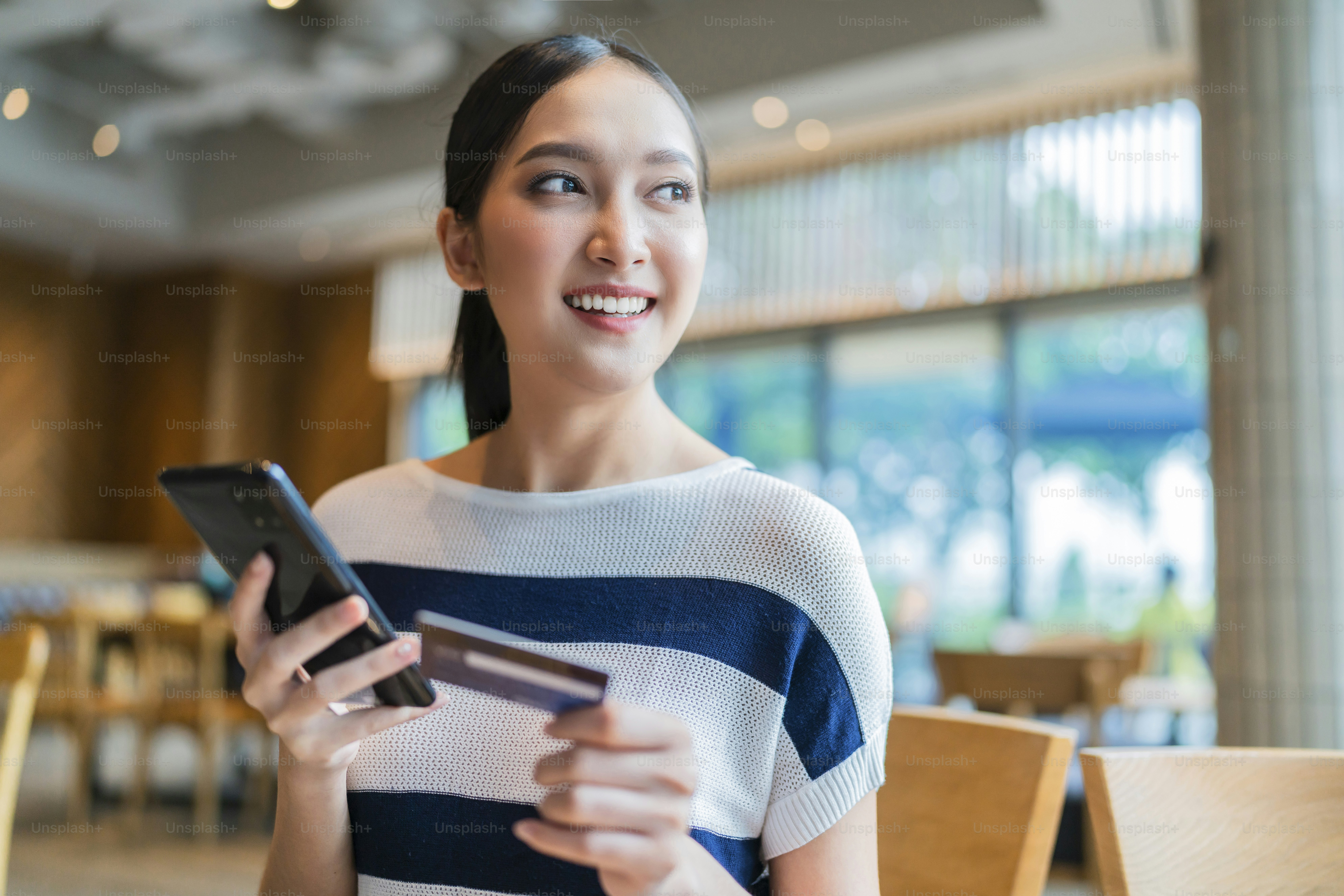 attractive adult asian female happiness shopping online with laptop hand hold credit card and smartphone for purchase product with background of building garden outdoor business ideas concept