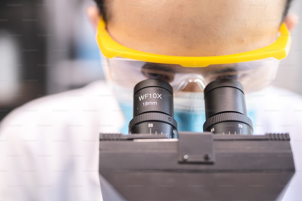 化学医学研究室で顕微鏡を使用したプロの研究者の集中、バイオテクノロジーまたは生物学実験用の医療科学技術機器を扱う技術者