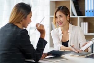 Two young Asian professional businesswomen working talking in a modern startup.