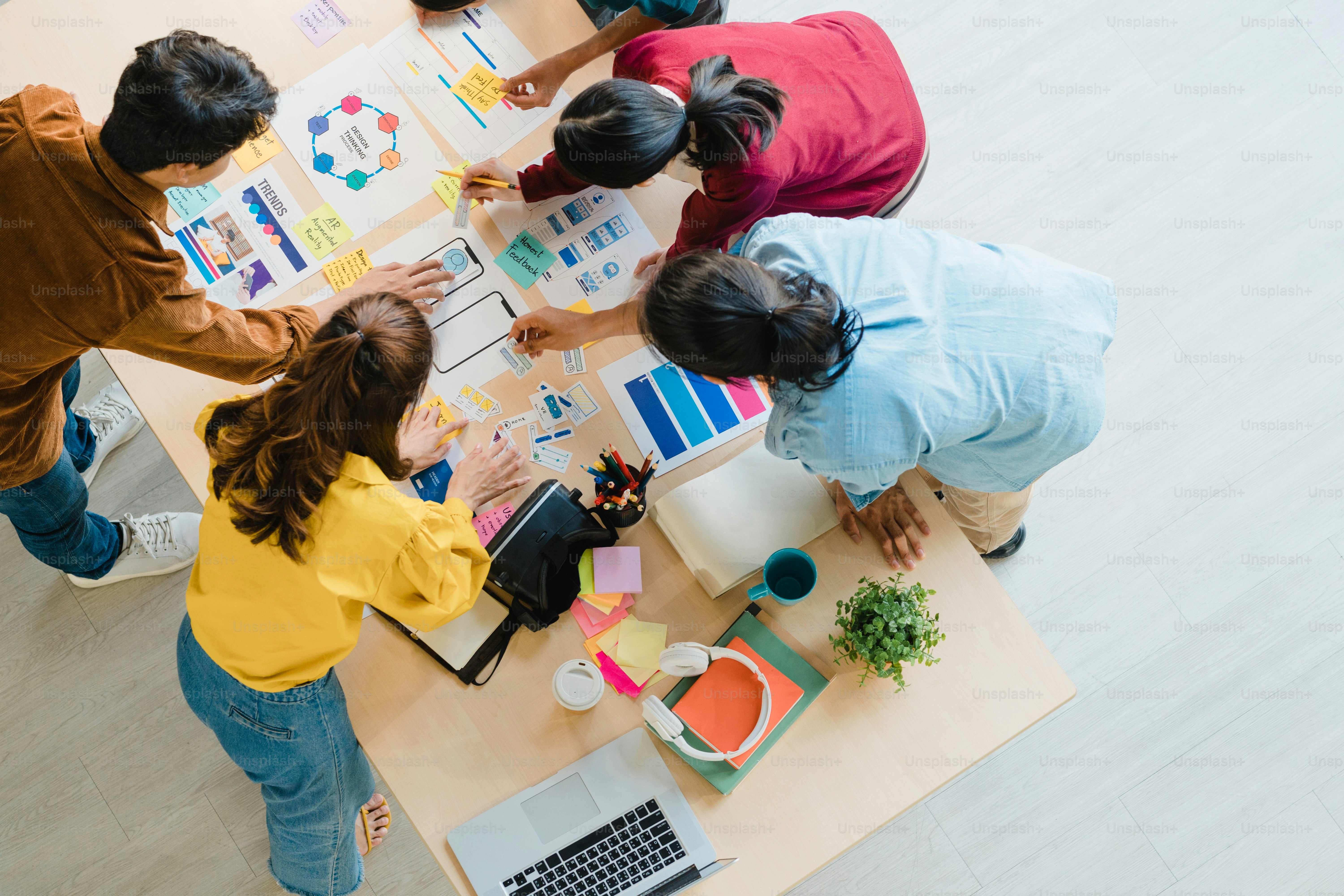 A group of people collaborating on design sketches at a large wooden table