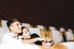 L'uomo caucasico e la coppia di affari della donna si rilassano vanno al cinema dopo il lavoro. Stanno guardando un film e mangiando popcorn. Concetto di attività di appuntamento romantico insieme
