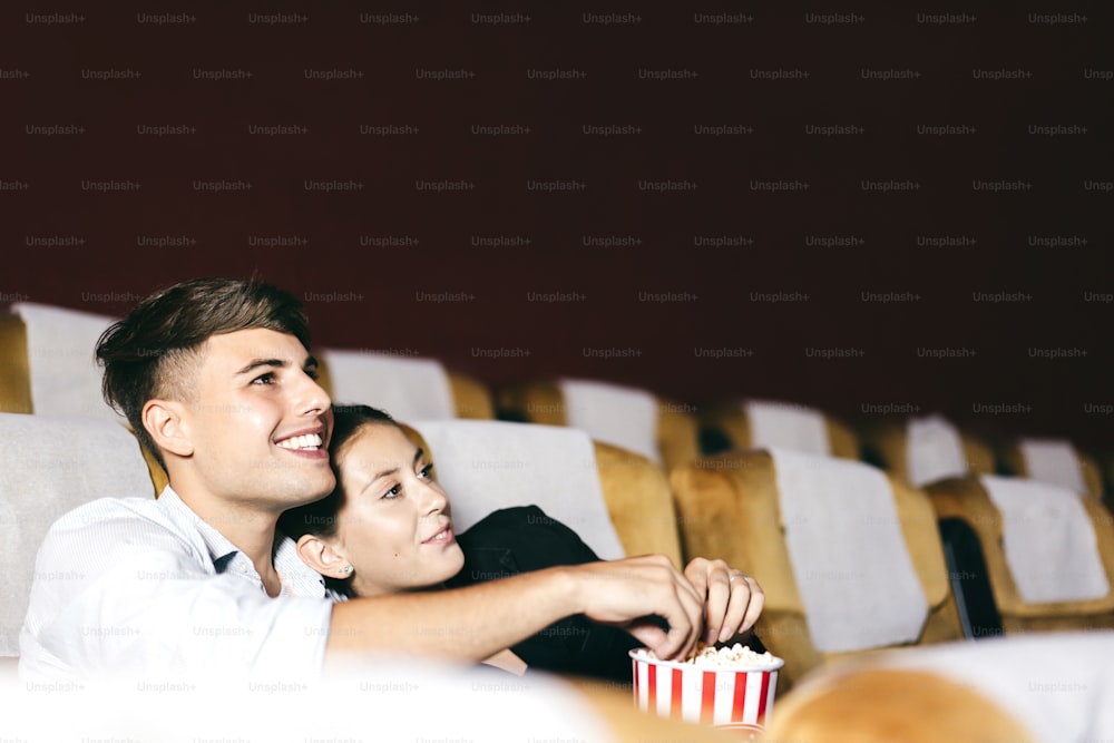 Caucasian man and woman business relax couple go to the cinema after work. They is watching a movie and eating popcorn. Together romantic date activity concept