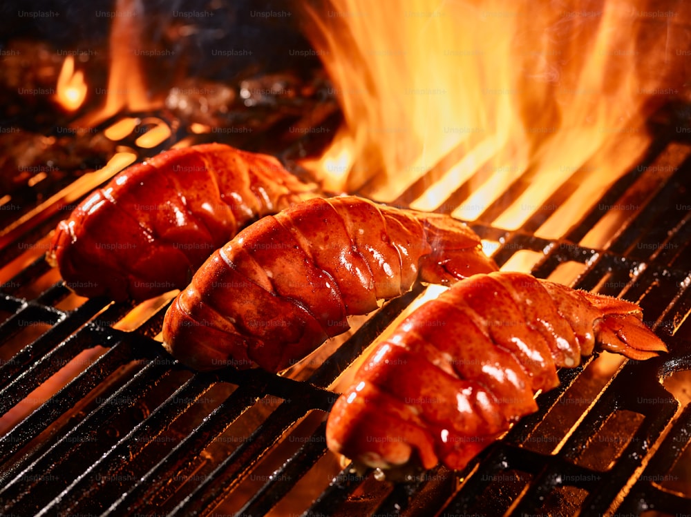 three lobster tails cooking on grill close up