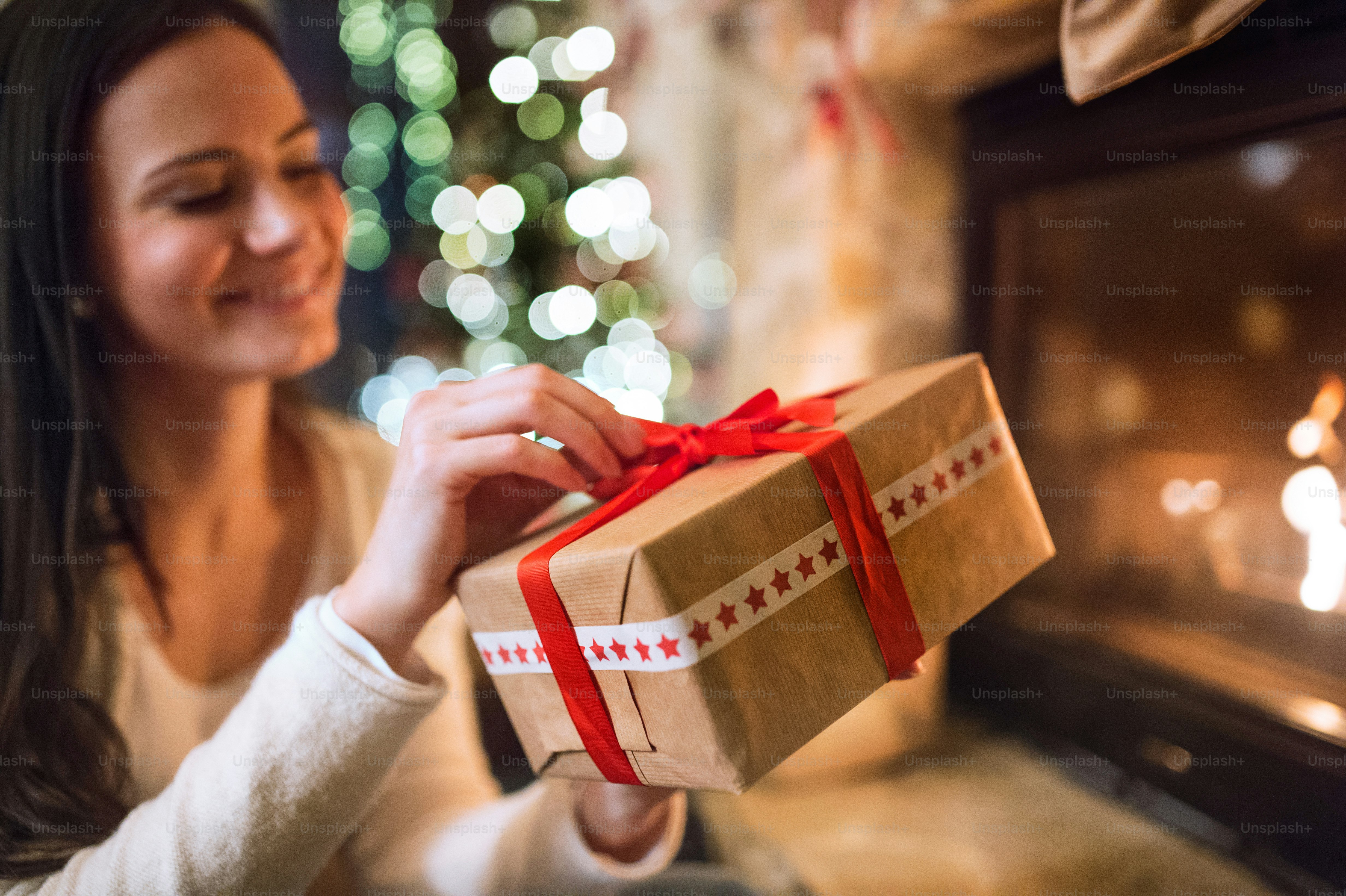 Young woman in front of fireplace holding Christmas present.