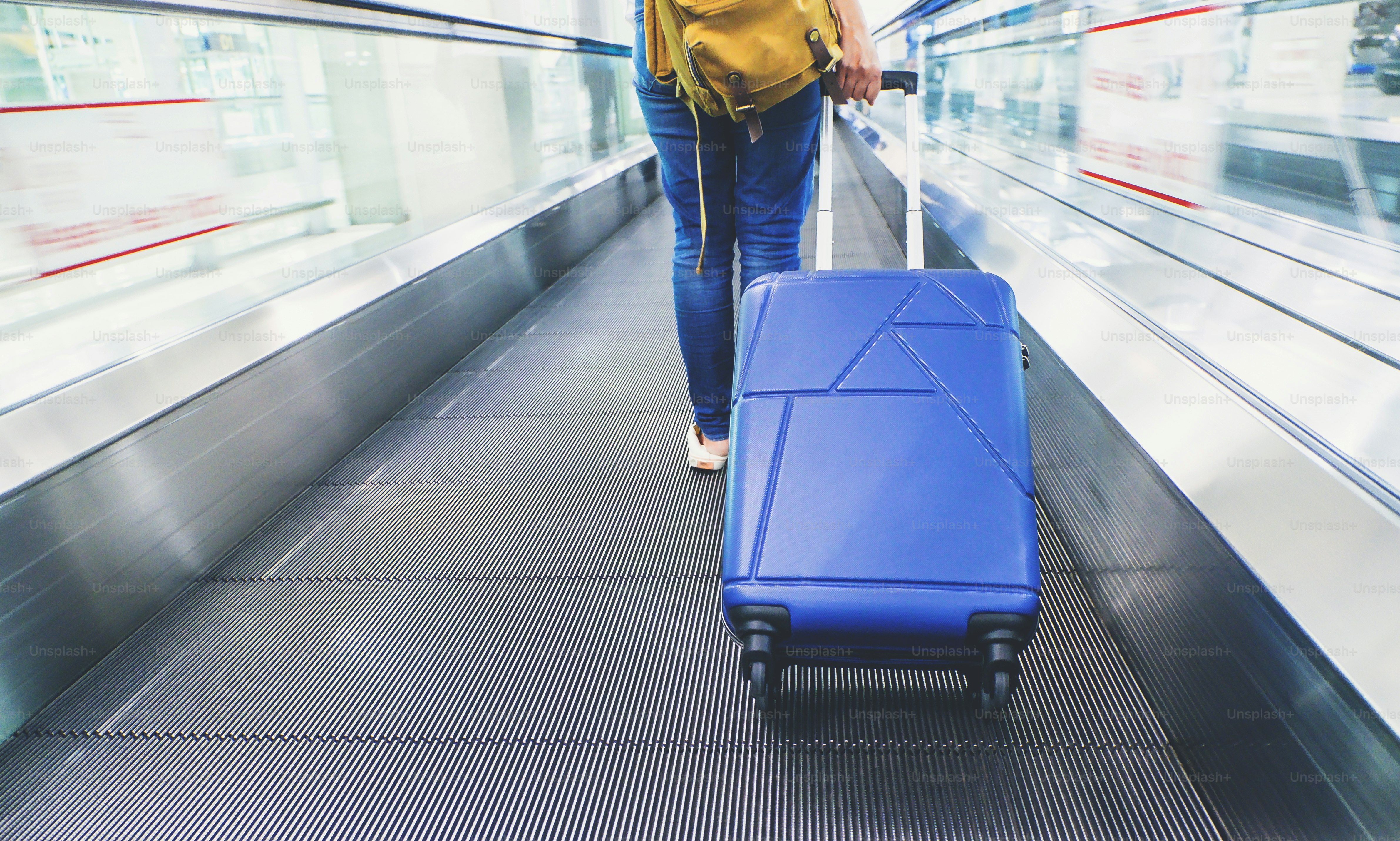 Traveler zieht Koffer zu Fuß auf der Schnellstraße am Flughafen mit Bewegungsunschärfe-Effekt, Reisekonzept.