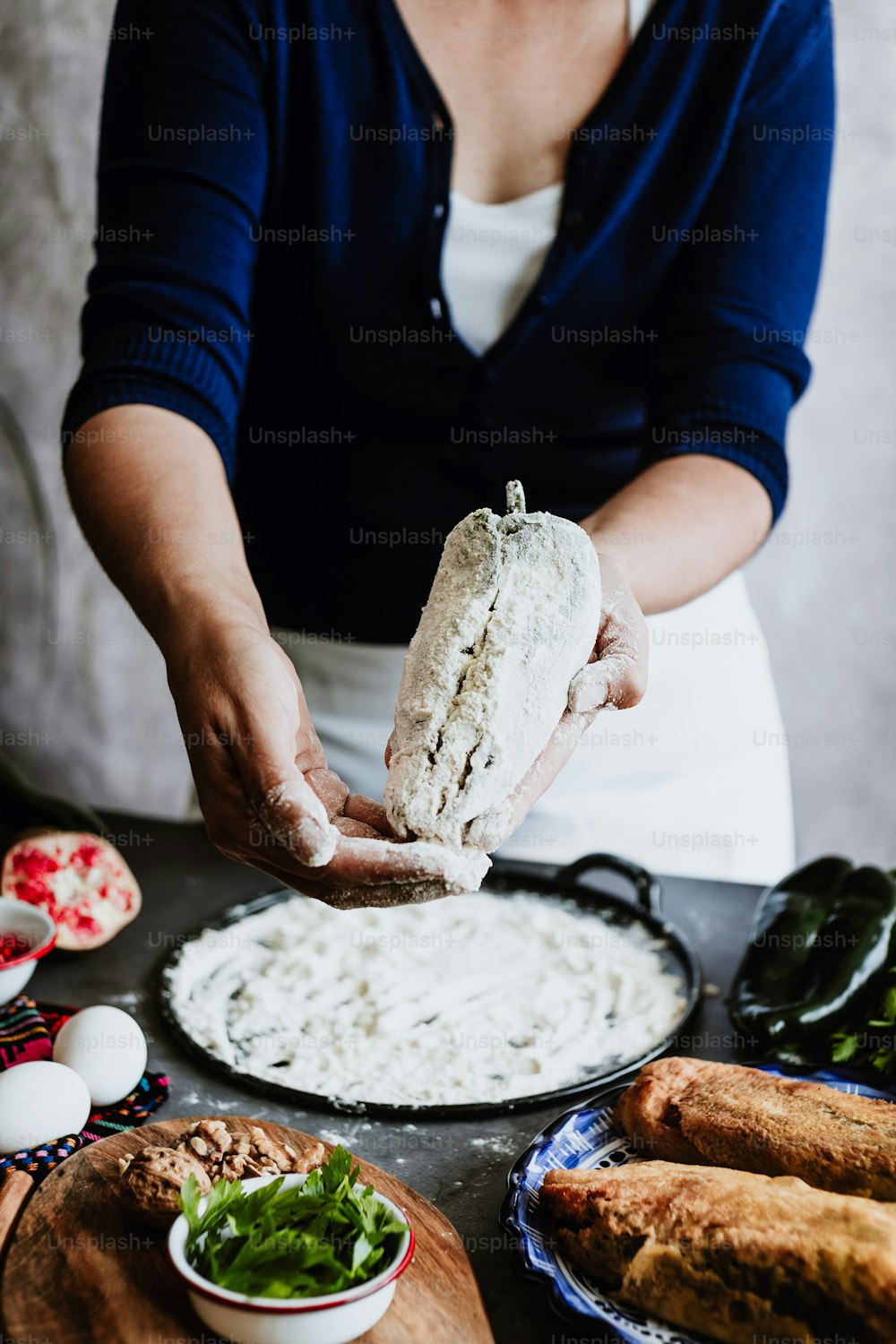 cooking mexican battered chiles en nogada recipe by woman hands with Poblano chili and ingredients, traditional dish in Mexico