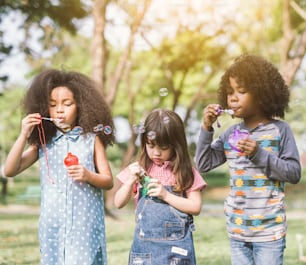 Gruppe von Diverse Kids süße Freunde, die Bubble-Spaß auf grünem Rasen im Park haben