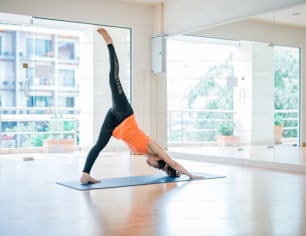 Retrato de una hermosa mujer joven disfrutando del yoga en el interior. Chica yogui haciendo ejercicio en el estudio de yoga Eka Pada Adho Muka Svanasana Pose, Larga Duración
