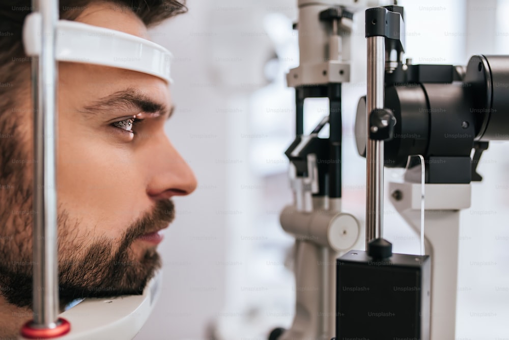 Handsome young man is checking the eye vision in modern ophthalmology clinic. Patient in ophthalmology clinic