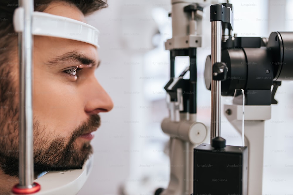 Um jovem bonito está verificando a visão ocular na moderna clínica de oftalmologia. Paciente em clínica oftalmológica