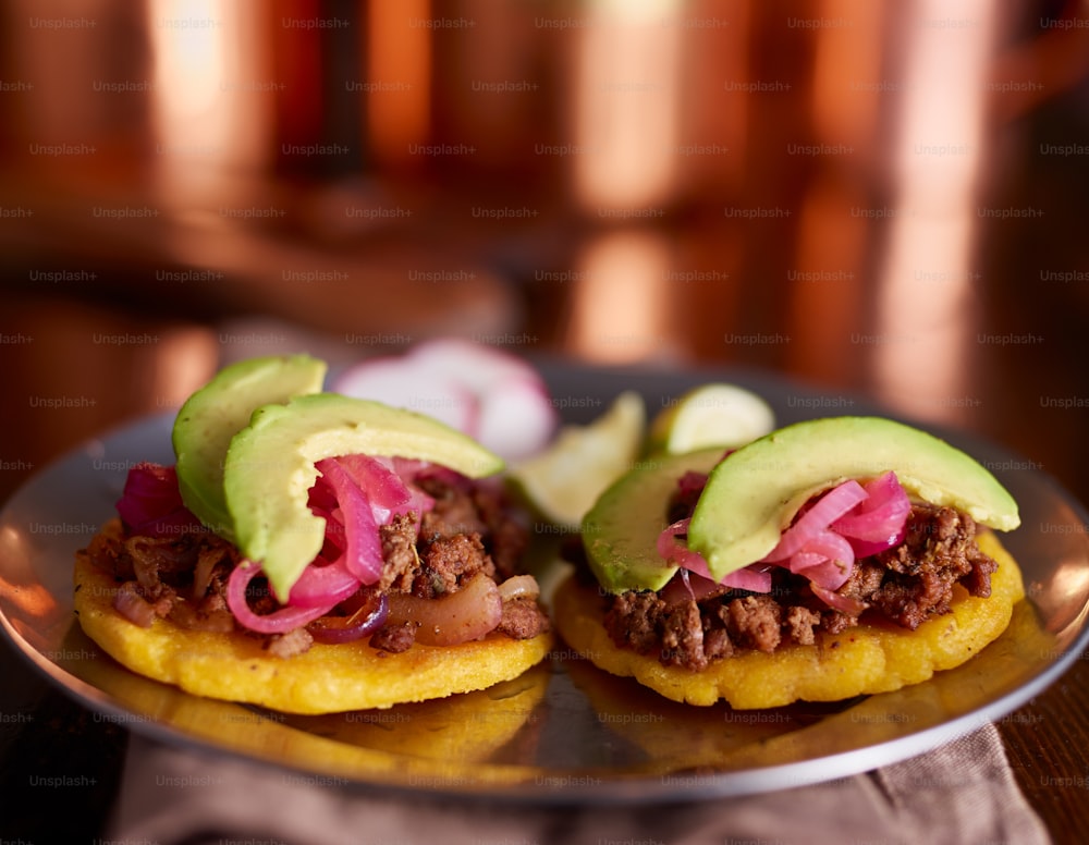 beef arepas with avocado and pickled onion on plate