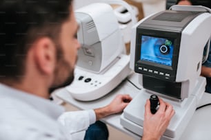 Handsome male doctor  ophthalmologist is checking the eye vision of attractive young woman in modern clinic. Doctor and patient in ophthalmology clinic.