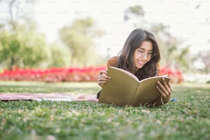 Portrait of high school girl lay down and read a book in park, education reading book concept