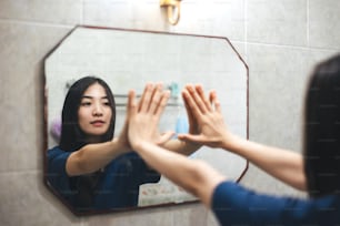 Junge Erwachsene lächeln asiatische Frau üben Selbstgespräch Gespräch mit Spiegel. Psychische Gesundheit im Badezimmer zu Hause. Gesunder Lebensstil nach dem Aufwachen mit Zufriedenheitskonzept.