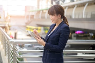 beautiful young asian business woman is using tablet in modern city