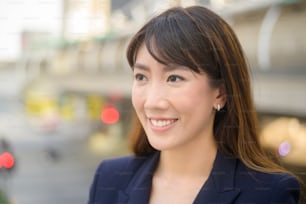 Retrato da bela mulher de negócios asiática jovem está trabalhando na cidade moderna