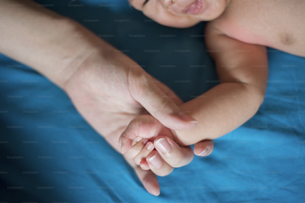 Close up da mão recém-nascida na mão da mãe enquanto dorme