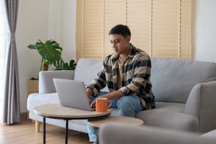 Young man working with laptop in living room at home