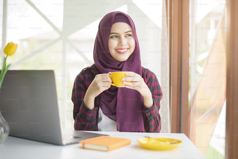Muslim woman with hijab is working with laptop computer in coffee shop